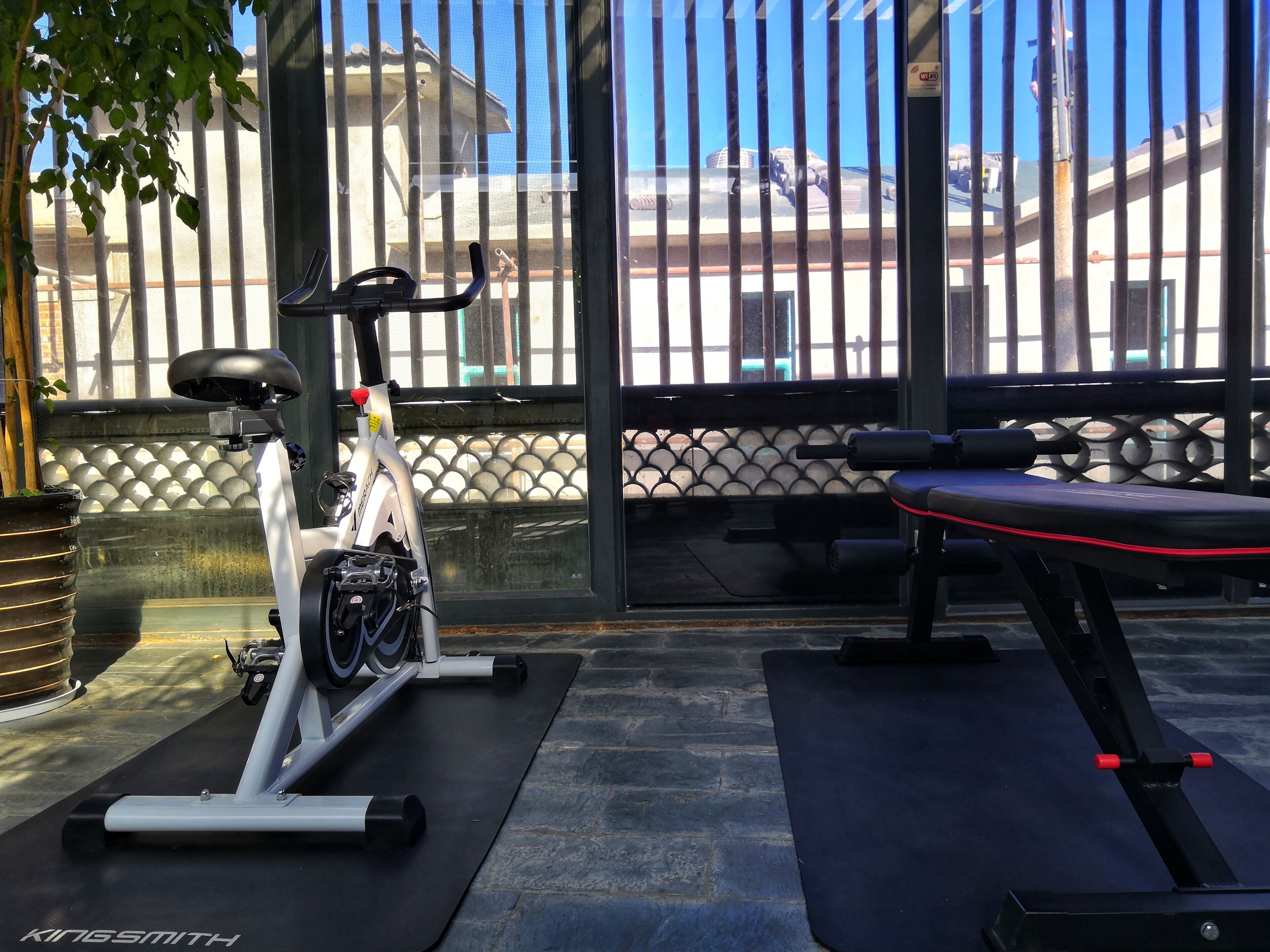 Ein Outdoor-Fitnessbereich mit Trainingsgeräten, darunter ein Crosstrainer und eine Bank.