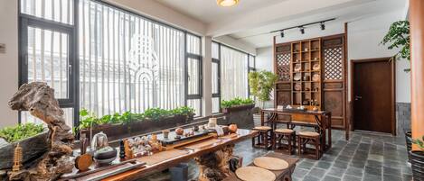 Una habitación amplia con una larga mesa de madera, ventanas grandes y un aparador de madera tradicional.