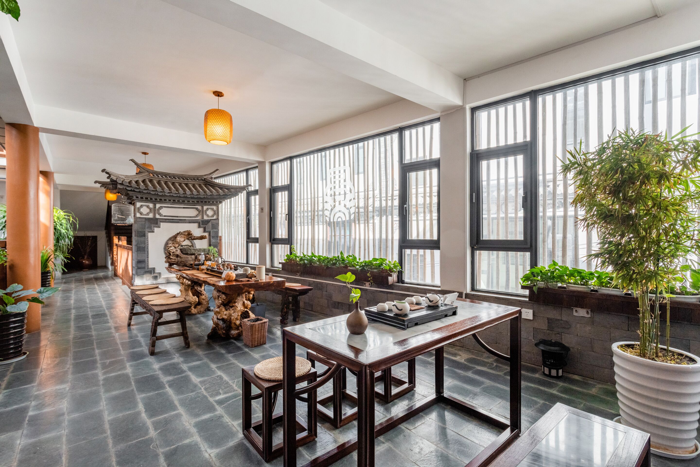 Un cuarto amplio con una mesa de madera tradicional, una planta grande en maceta y vistas a través de amplios ventanales.