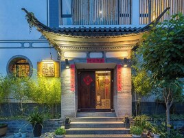 Un edificio tradicional chino con techo de tejas, puerta de madera y caracteres chinos sobre la entrada.
