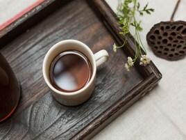 Una taza blanca de té sobre una bandeja de madera con un adorno y una planta pequeña.