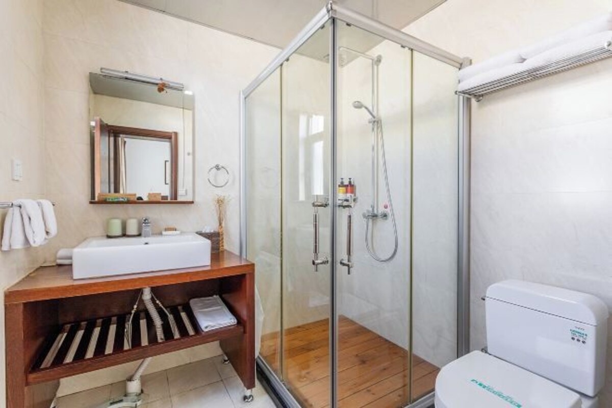 A modern bathroom with a glass-enclosed shower, a wooden vanity with a sink, and a toilet.