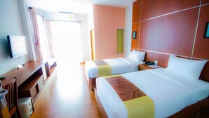 Habitación de hotel con dos camas, un escritorio, televisión y ventana con cortinas.