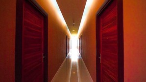 Un pasillo con puertas rojas y una luz brillante al final.