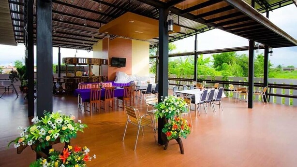 Comedor interior con mesas, sillas, un televisor y vista a la vegetación exterior.
