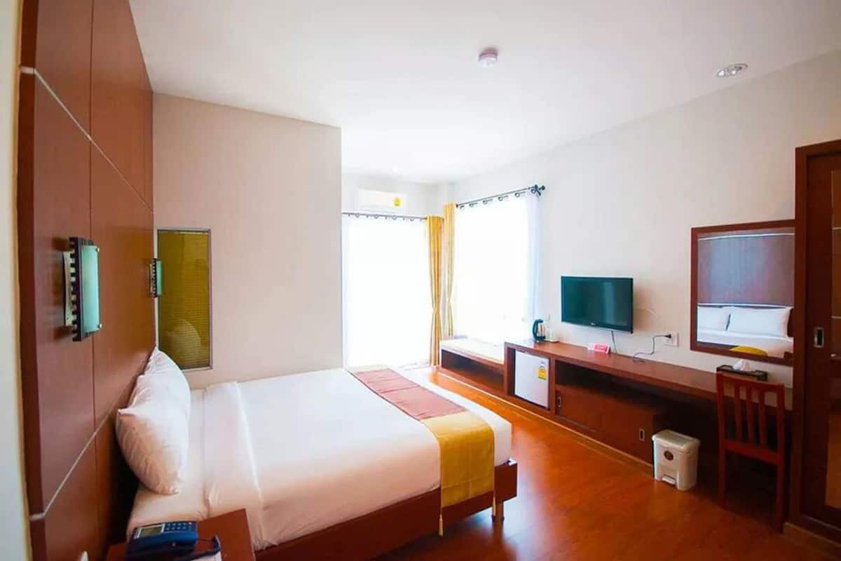 A hotel room with a bed, a desk, a television, and a window with curtains.