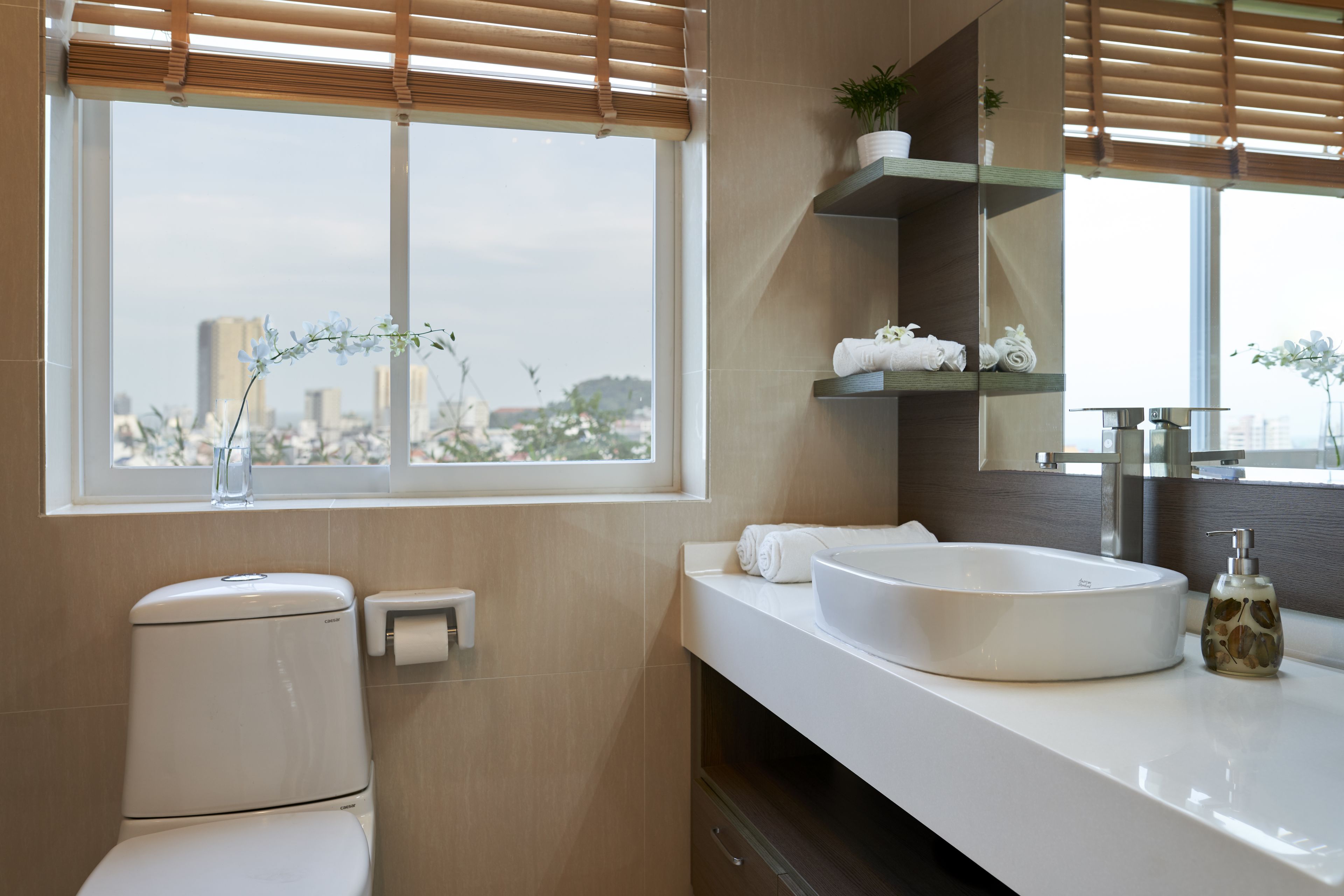 A modern bathroom with a toilet, sink, and window with blinds.