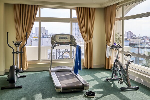 A hotel room with a treadmill, stationary bike, and a massage table.