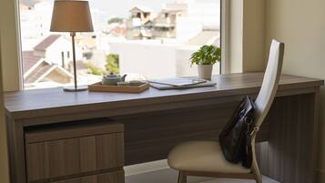 A modern desk with a lamp, a potted plant, and a laptop.