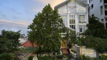 A boutique hotel with a prominent sign, a staircase leading to the entrance, and lush greenery surrounding the property.