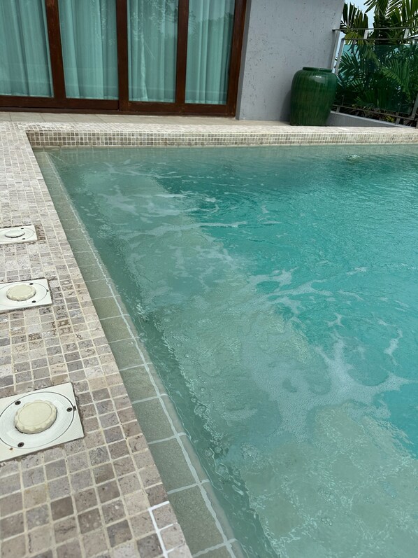 Piscina con bordes azulejados y una cubierta para desagüe.