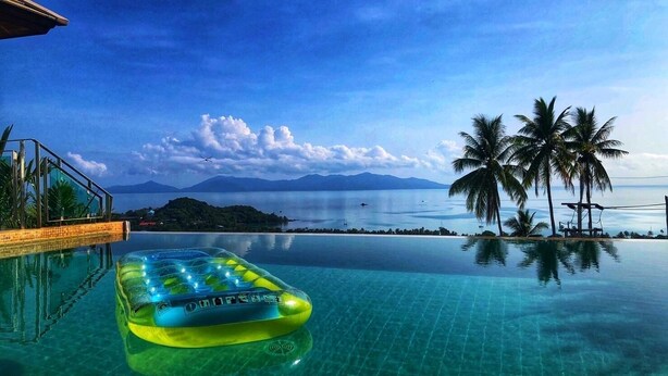 A clear pool with a floating platform, palm trees, and a distant view of mountains and the sea. - 180 ‘ seaview fisherman bophut night market north coast, betwen Meanam Chaweng , (Bophut)