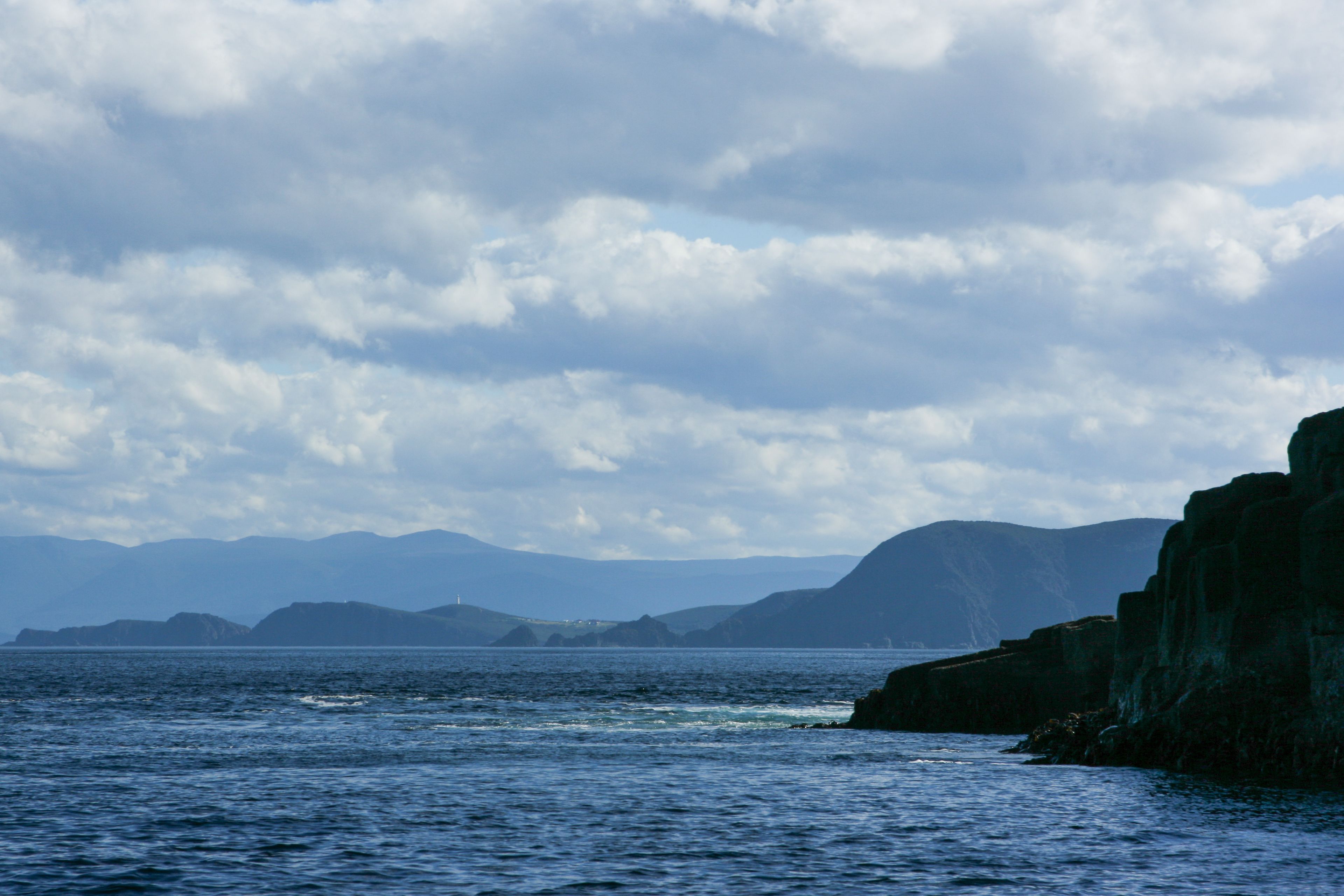 A coastal landscape with rocky cliffs and a calm sea.