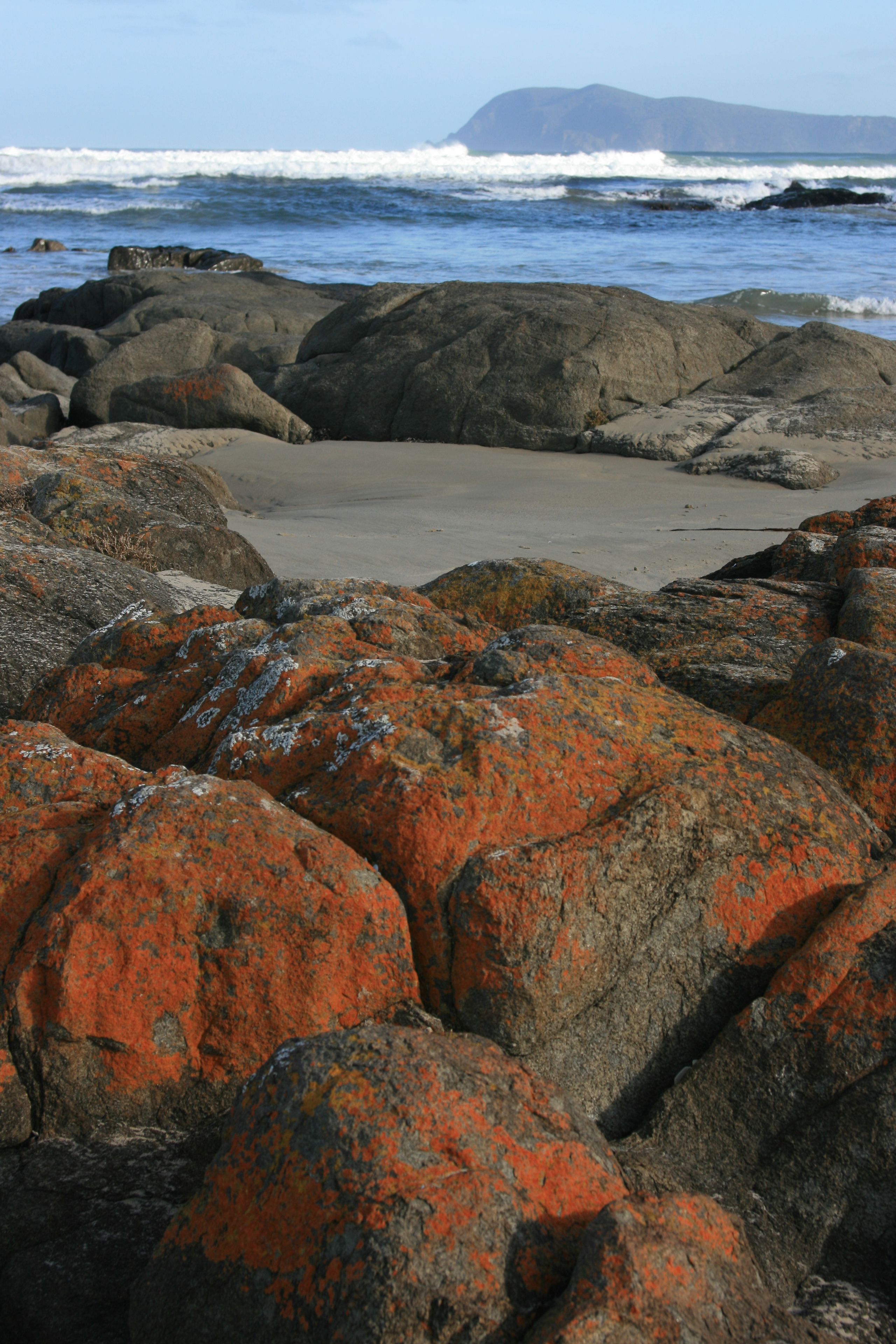 A rocky shoreline with large boulders and a view of the ocean.