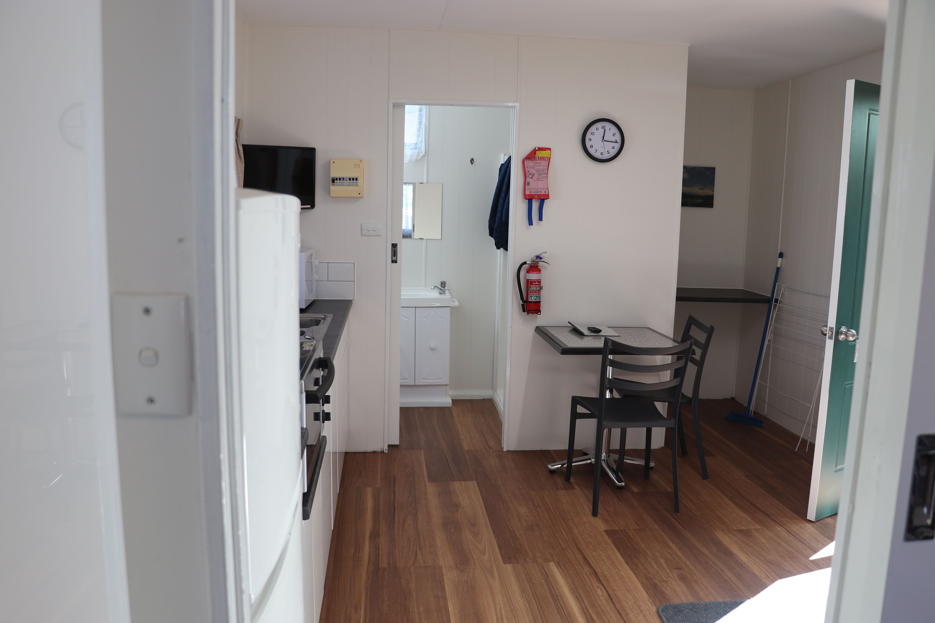Una cocina compacta con comedor, microondas, pileta y extintor.