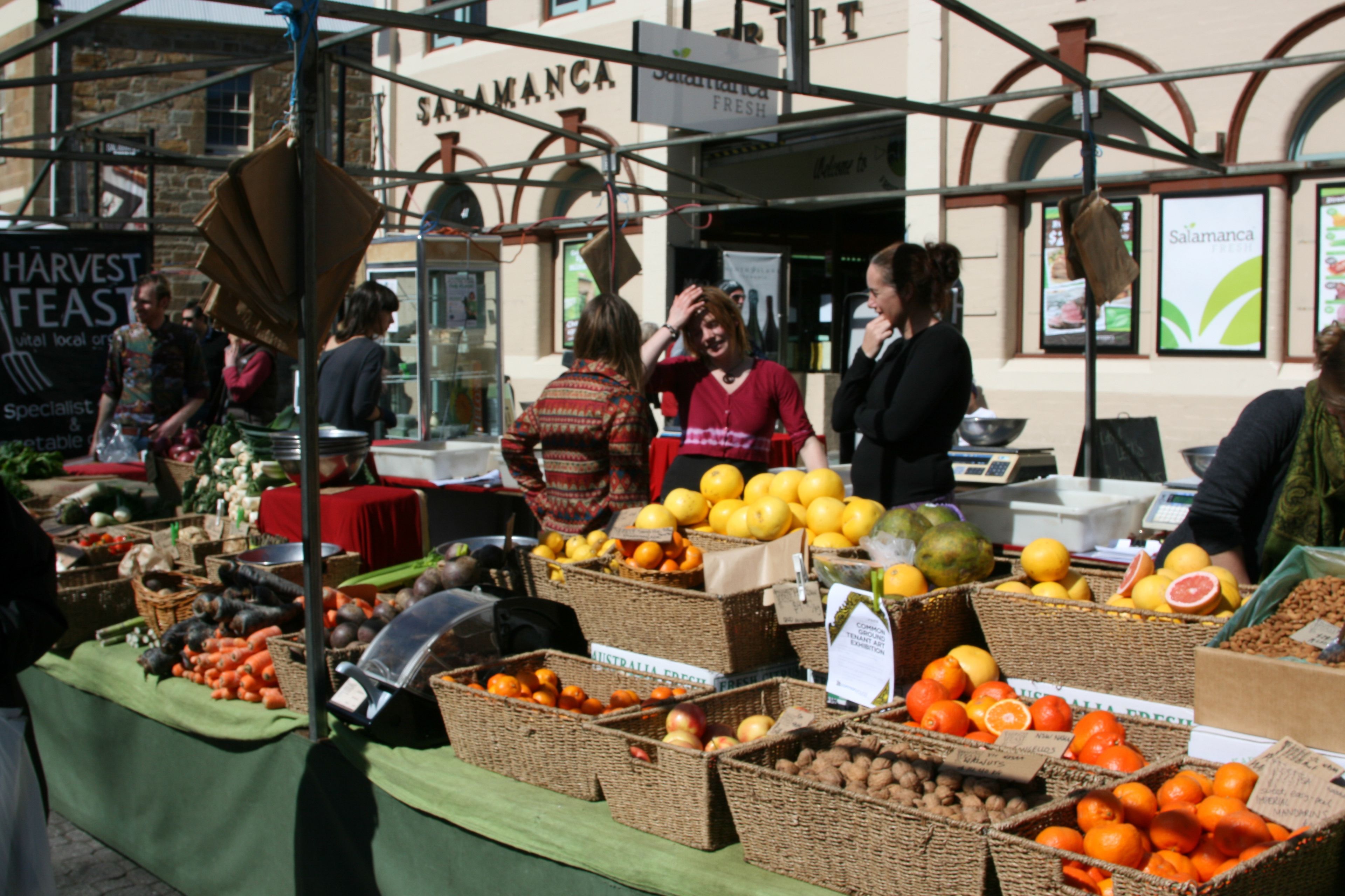 Un étal de marché où sont présentés divers fruits et légumes dans des paniers.