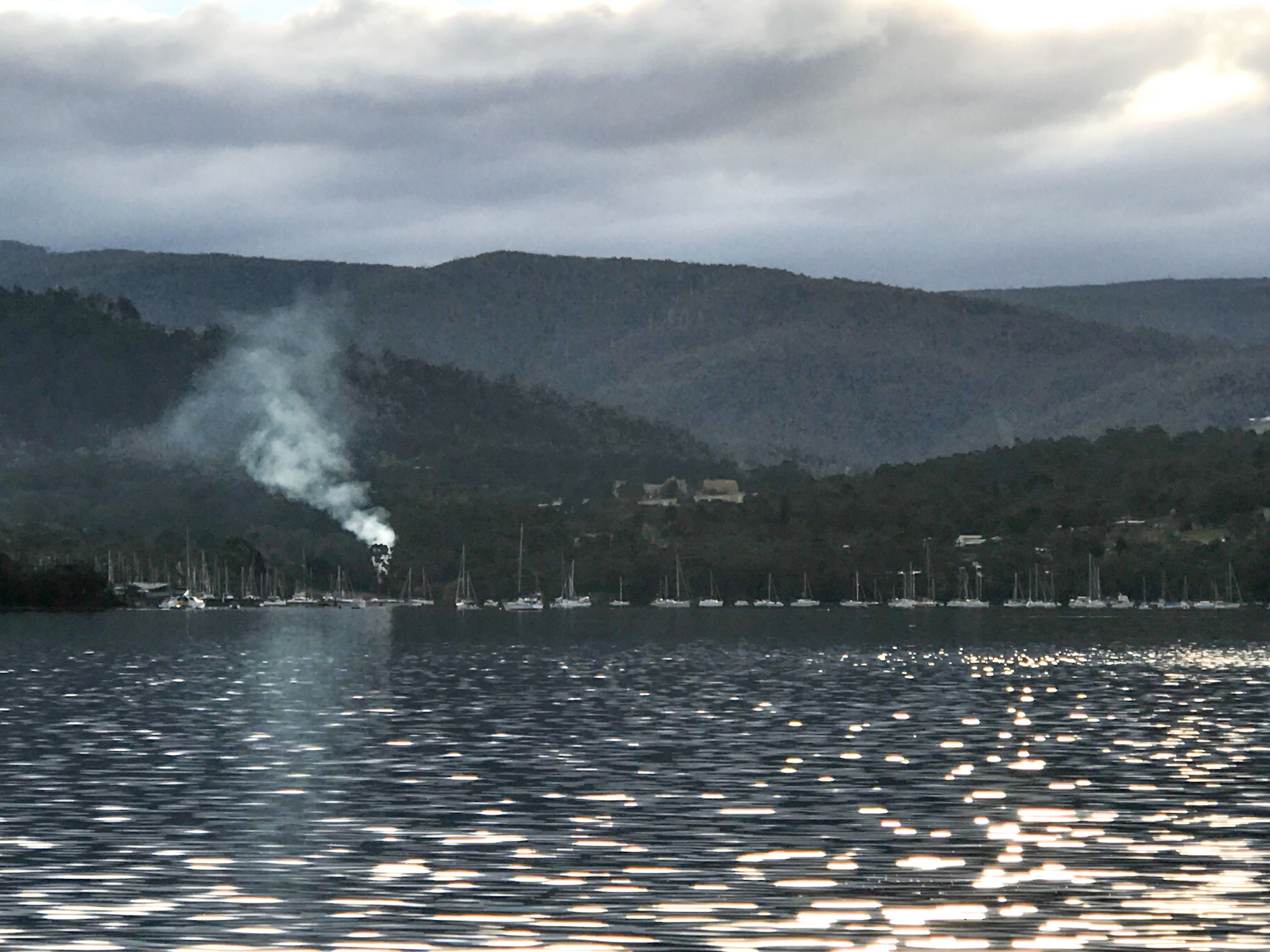 A lake with boats and a distant building on a hill.