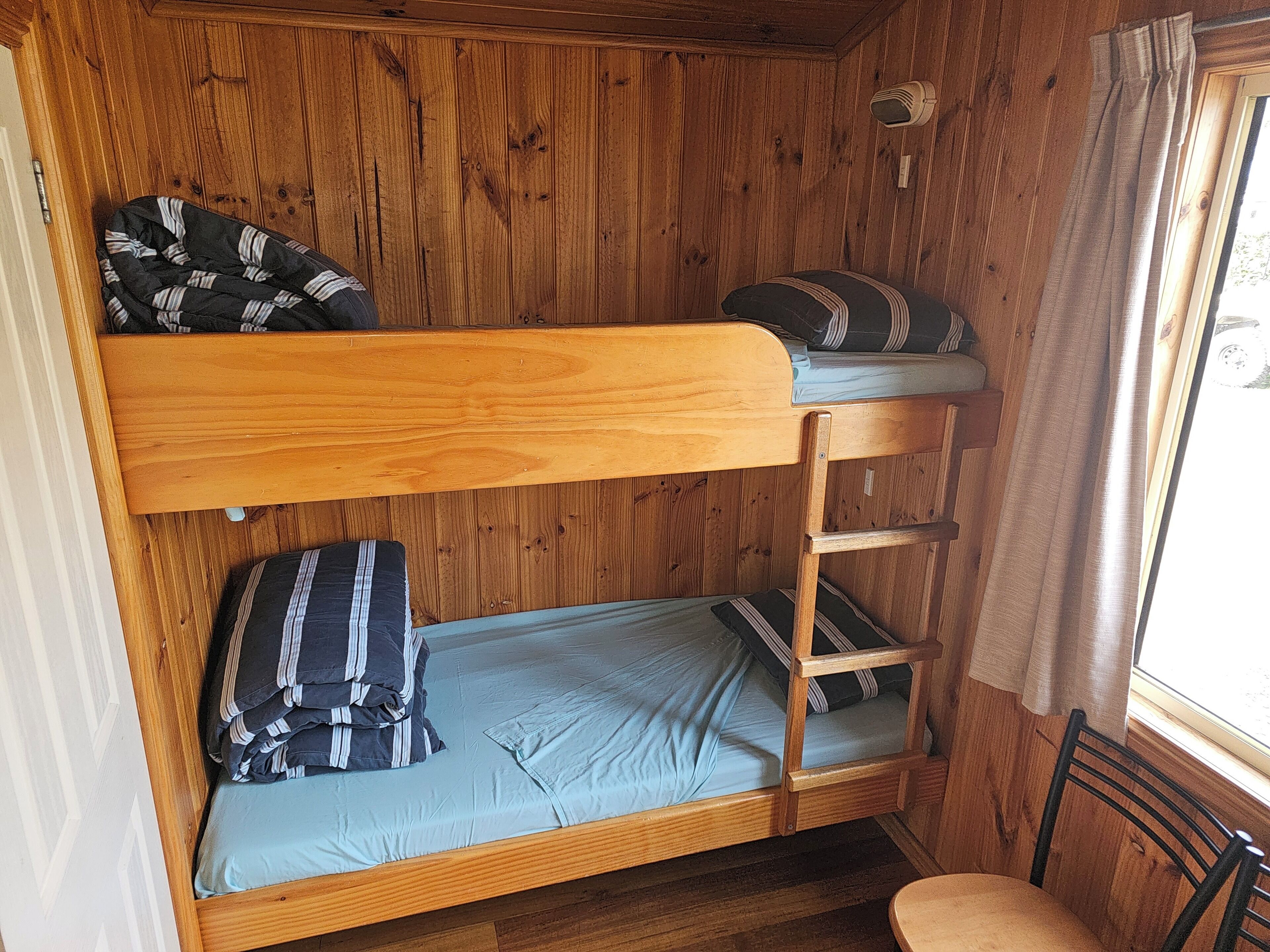 A bunk bed with a wooden frame and a window with curtains.