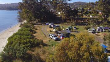 A campsite with RVs and tents, a beach, and hills in the background.