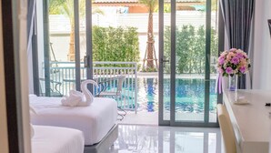 A hotel room with two beds, a view of a swimming pool, and a balcony with a railing. - Baan Yamoo Ranong (Ranong)