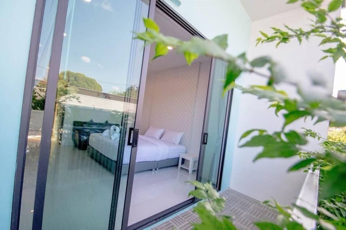 A modern bedroom with a glass door, a bed, and a small bedside table.