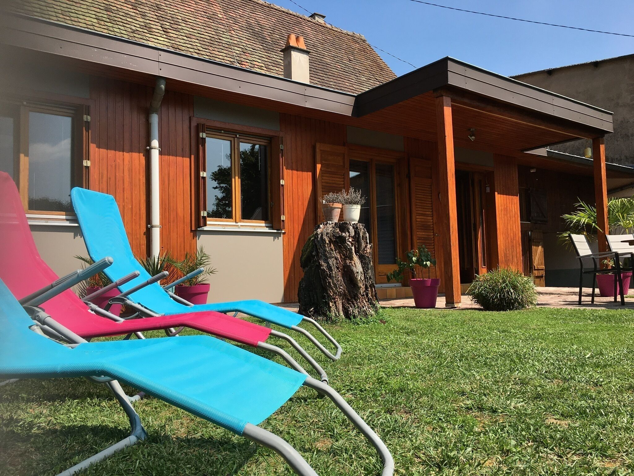 Ein modernes Haus mit Holzfassade, einer überdachten Veranda und einem gepflegten Rasen.