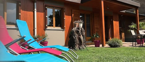 A modern house with a wooden facade, a covered porch, and a well-maintained lawn.