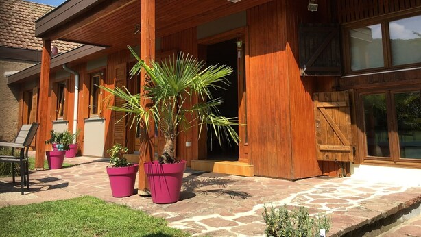 A modern building with a covered porch, wooden columns, and large windows.