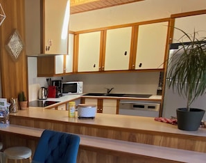 Una cocina compacta con armarios de madera, microondas, cafetera y pileta.