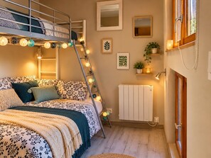 Un dormitorio acogedor con literas, una escalera, lámparas de noche, un radiador y estantes con plantas.