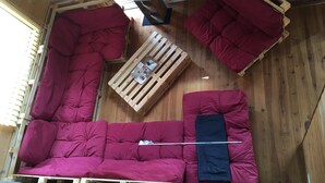A room with a wooden floor, a red sofa, a wooden coffee table, and a window with blinds. - Ideal house for 4 families with 2 children each  (Montgeron)