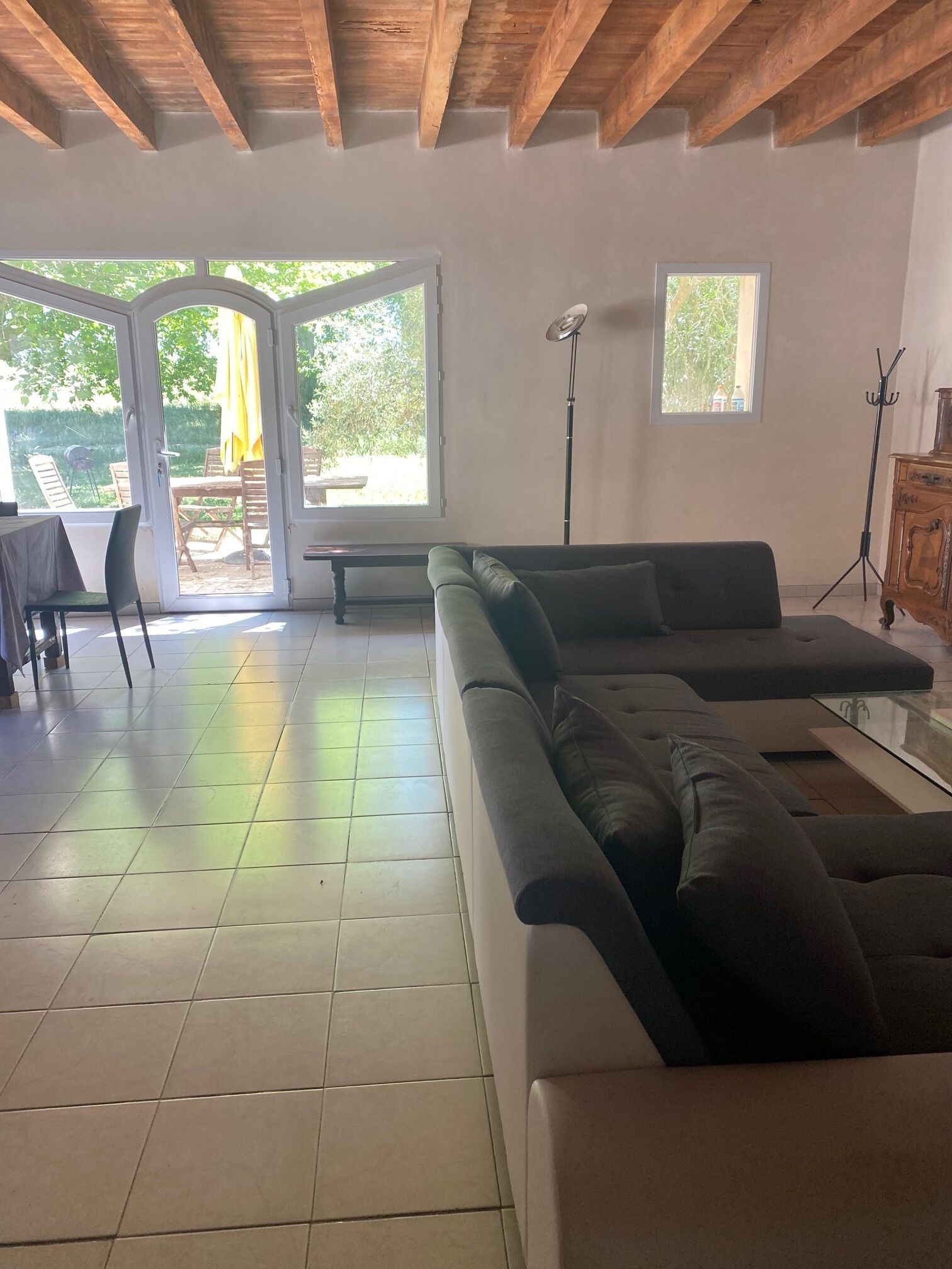 Un vaste espace de vie comprenant un canapé d’angle, une table à manger avec des chaises, et un patio avec une table et des chaises.