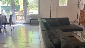A spacious living area with a sectional sofa, a dining table with chairs, and a patio area with a table and chairs. - Gîtes in Camargue (Arles)