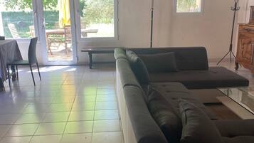 Un vaste espace de vie comprenant un canapé d’angle, une table à manger avec des chaises, et un patio avec une table et des chaises.