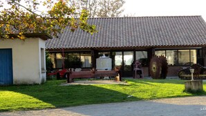A rustic building with a tiled roof, a bench outside, and a large water wheel. - Gîtes in Camargue (Arles)