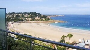 A coastal view with a beach, ocean, and buildings in the background. - Nice apartment with sea view a few meters away and balcony, close to shops. (Perros-Guirec)