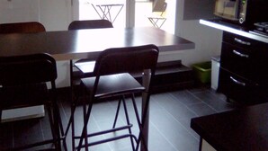 Une cuisine compacte comprenant une table à manger, des chaises, un four à micro-ondes et un petit réfrigérateur.