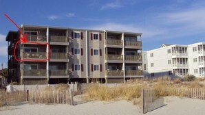 A multi-story building with balconies, located near a sandy beach. - Comfy Direct Oceanfront Condo.  Our Happy Place can be Yours. Book a great deal! (North Myrtle Beach)
