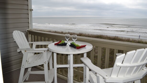 A white table with two chairs on a balcony overlooking the ocean. - Comfy Direct Oceanfront Condo.  Our Happy Place can be Yours. Book a great deal! (North Myrtle Beach)
