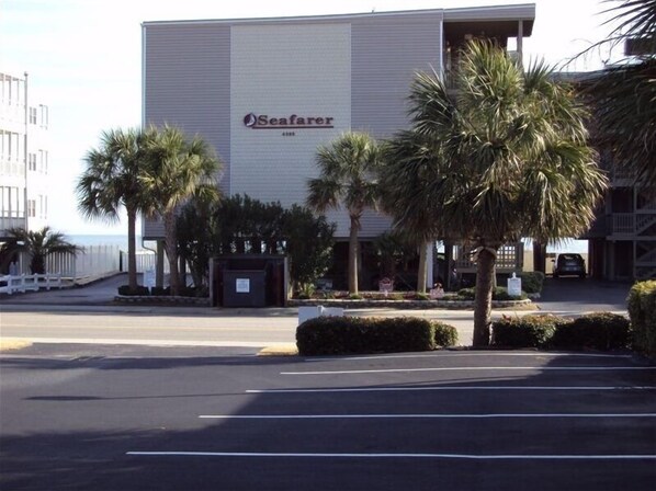 A Seafarer hotel with a large building, palm trees, and a parking lot. - Comfy Direct Oceanfront Condo. Our Happy Place can be Yours. Book a great deal! (North Myrtle Beach)