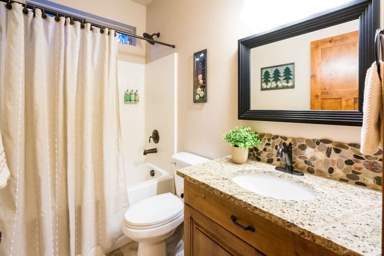 Une salle de bain équipée d’une douche, de toilettes, d’un lavabo et d’un miroir.
