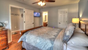 A bedroom with a bed, a ceiling fan, a television, and a dresser.