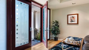 A room with a sliding glass door leading to an outdoor area, a potted plant, a framed artwork on the wall, and a bed with a patterned bedspread. - 🏖️Mauna Lani Townhome w/ Beach Club Access + A/C (Kamuela)