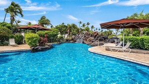 A clear blue pool with lounge chairs and umbrellas, surrounded by tropical vegetation and a waterfall feature. - 🏖️Mauna Lani Townhome w/ Beach Club Access + A/C (Kamuela)