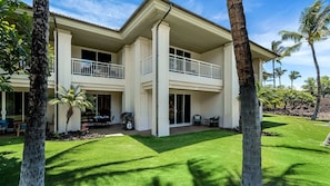 A two-story house with a balcony, a patio with outdoor furniture, and a well-maintained lawn. - 🏖️Mauna Lani Townhome w/ Beach Club Access + A/C (Kamuela)