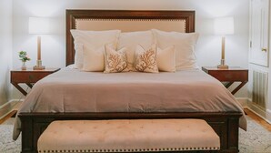 A neatly made bed with a wooden headboard, two bedside tables with lamps, and a bench at the foot of the bed. - Only 1 block to FRONT BEACH! Perfect location in Ocean Springs! The King Suite (Ocean Springs)