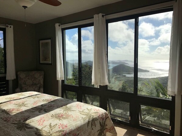 A bedroom with a large window offering a view of a mountainous landscape and a body of water. - Villa Ixora Sleeps 2-10 people~ 5 bedrooms, 4 baths, pool, AMAZING views! (St.john)