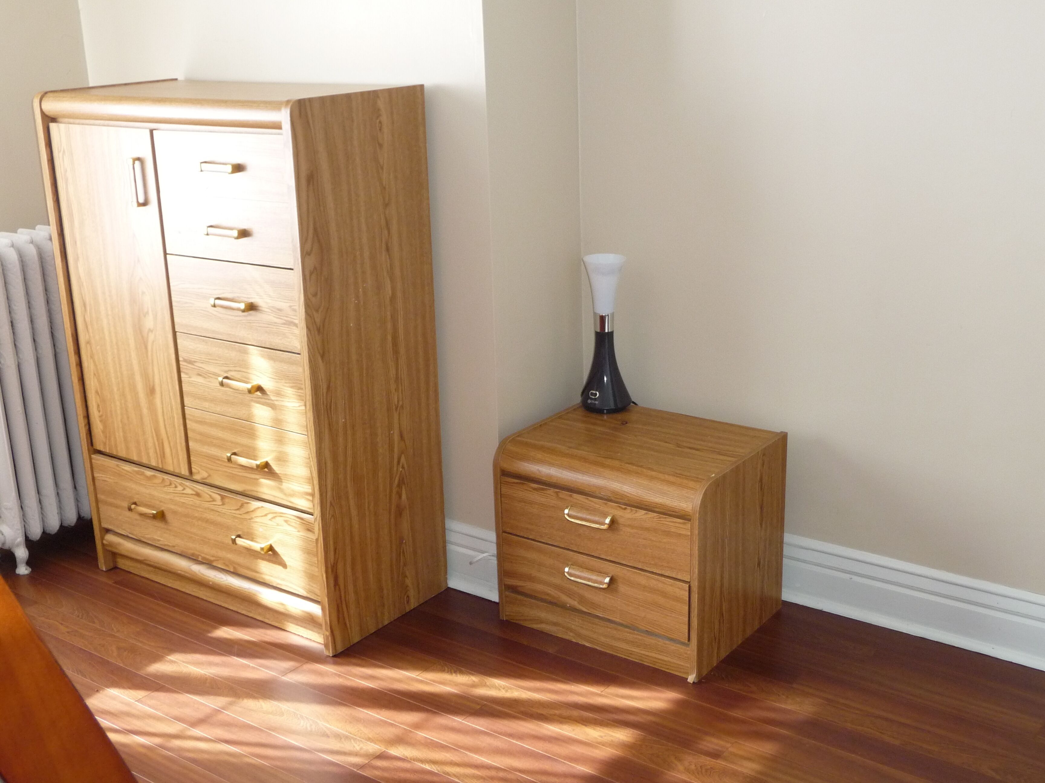 A wooden wardrobe with multiple drawers and a smaller chest of drawers beside it.