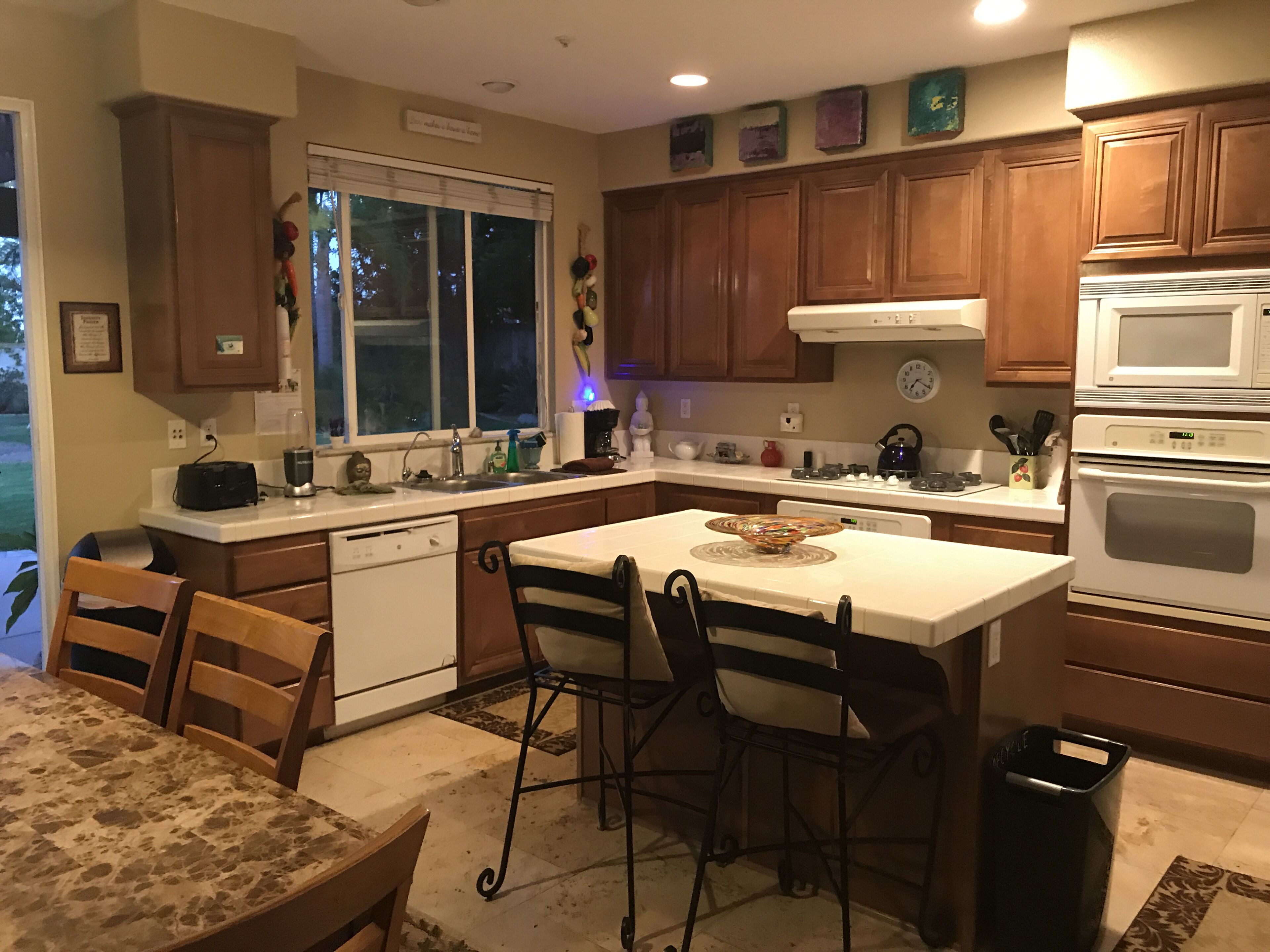 A kitchen with wooden cabinets, a dishwasher, a sink, and a dining area with a table and chairs.