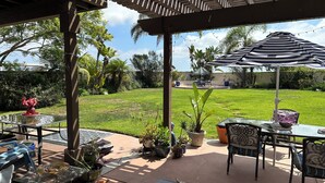 A covered patio area with outdoor furniture, a dog, and a grassy yard in the background. - Legoland Beach 1.5mi canyon golf  Four Seasons Aviara Carlsbad-1/2 acre- (Carlsbad)